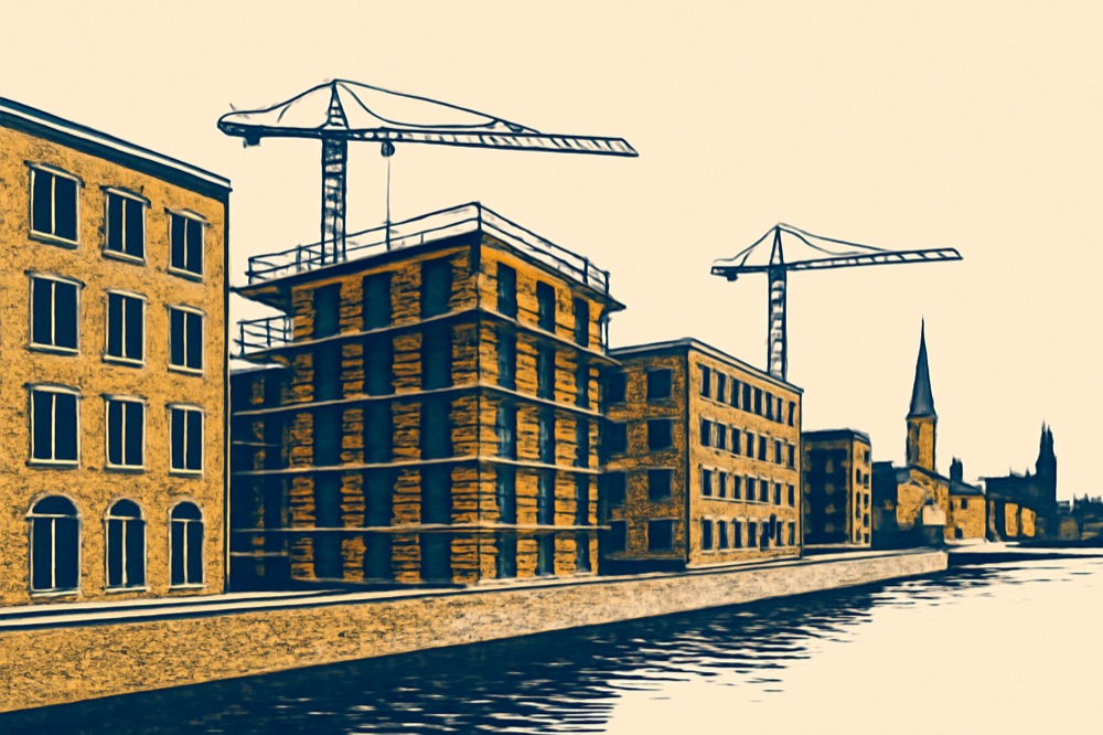 Cranes over mid‑rise apartment construction on a German city canal