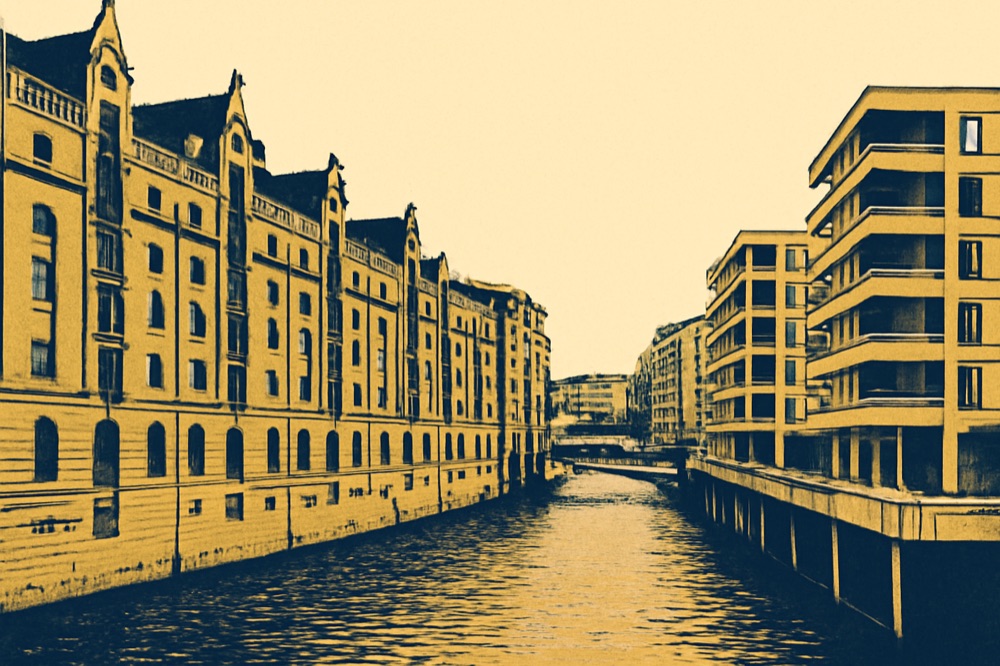 HafenCity‑Eigentumswohnungen und Speicherstadt‑Backsteinblöcke an einem Kanal in Hamburg.