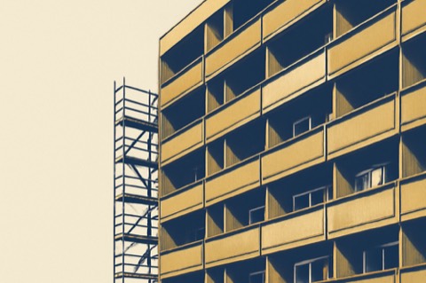 German condo facade with balconies, one showing a small split A/C outdoor unit and a scaffold for balcony works