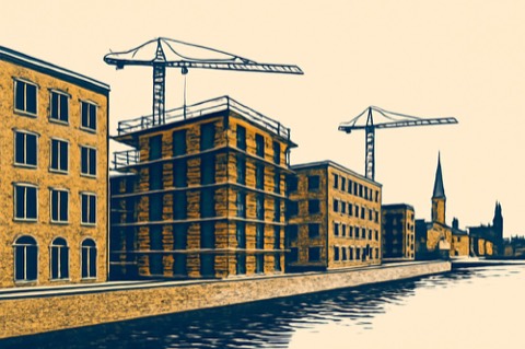 Cranes over mid‑rise apartment construction on a German city canal